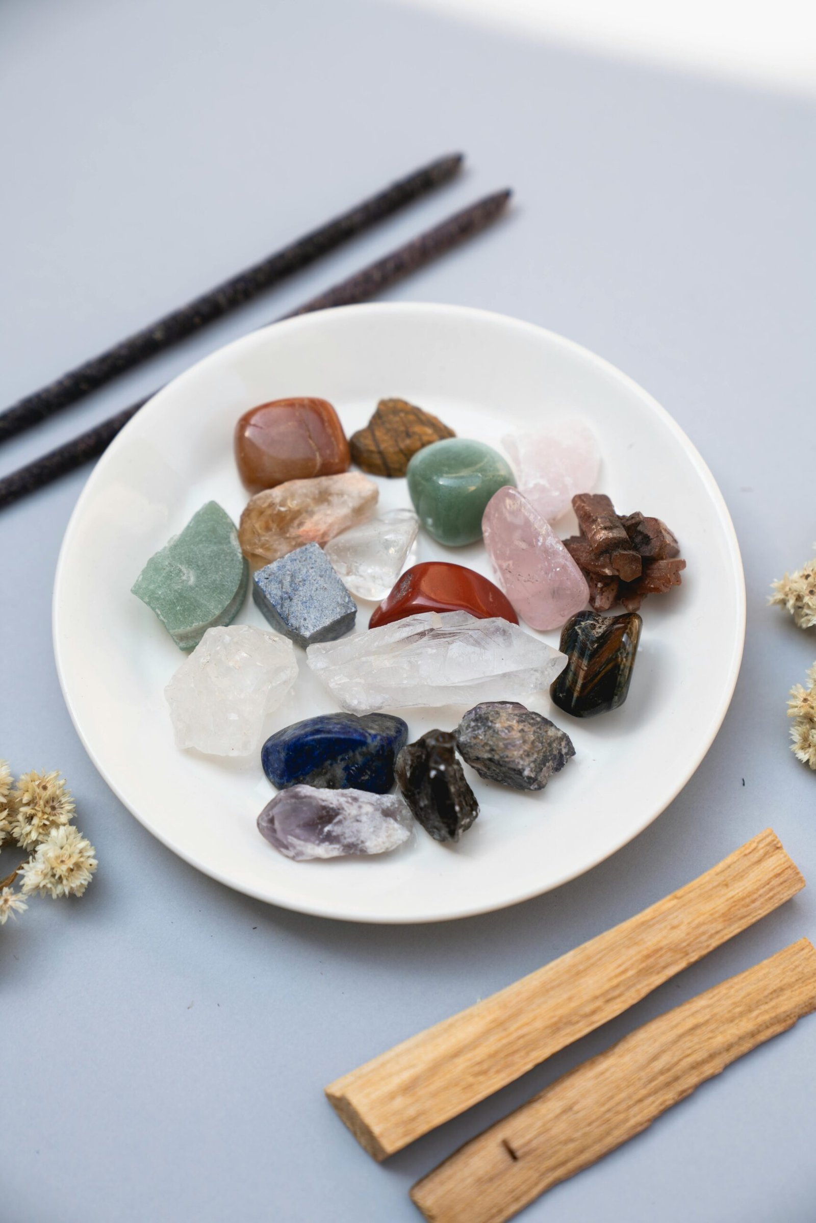 A collection of colorful healing crystals displayed on a white ceramic plate for spiritual therapy.